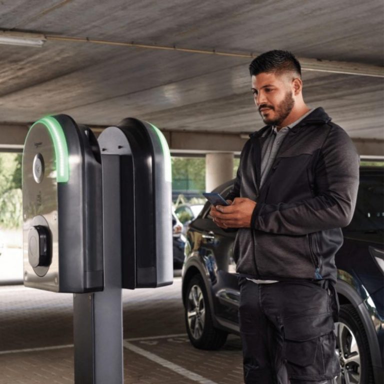 Man looking at Schneider EVlink Pro AC charger at a public car park