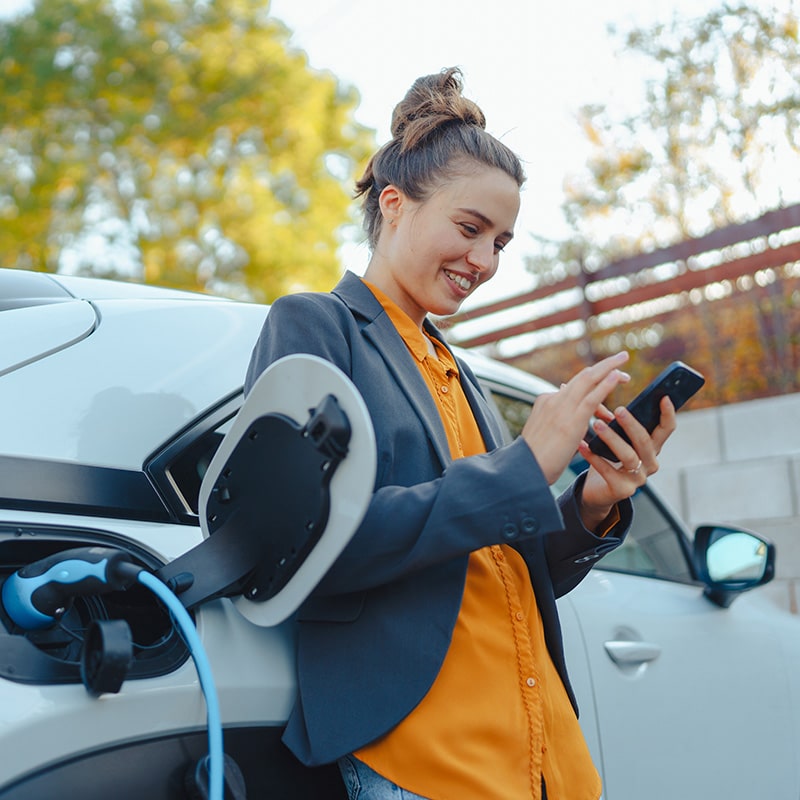 girl leaning against electric car while it charges